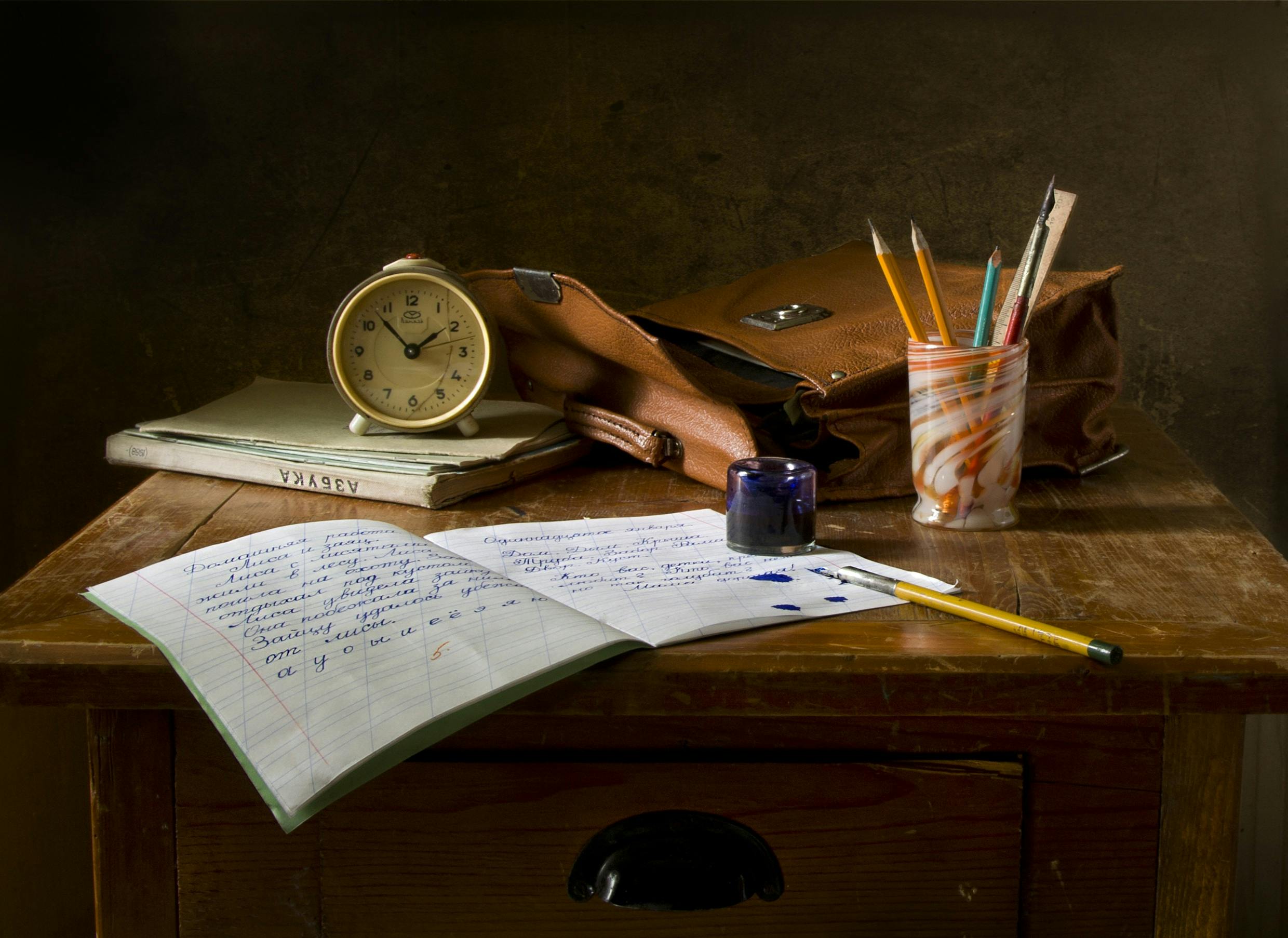 PSZICHOLÓGUS BLOG 7 Classic wooden desk with writing materials, vintage clock, and a leather bag.